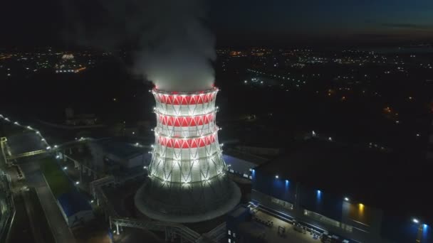 Torre de enfriamiento panorámica aérea contra ciudad oscura al atardecer — Vídeo de stock