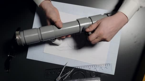 Mitarbeiter dreht Schraube an neuem Rohr über Zeichnung — Stockvideo