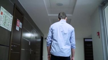 Merkezi koridor boyunca arka görünümü genç adam yürüyor