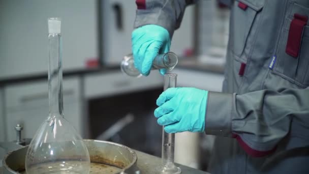 Closeup lab assistent giet vloeistof in het bekerglas op tafel — Stockvideo