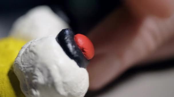 Macro man zet kleine rode spelen deeg stukken op bee grappige ogen — Stockvideo