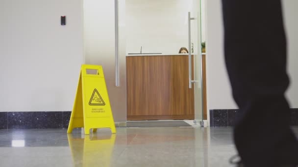 Businessman comes into office past sign wet floor backside — Stock Video