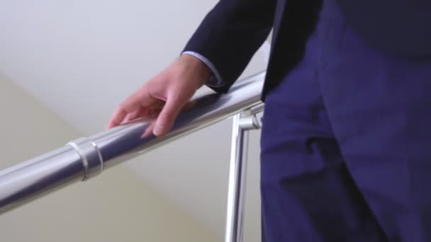 Человек держится за перила и спускается по лестнице замедленной съемки — стоковое видео