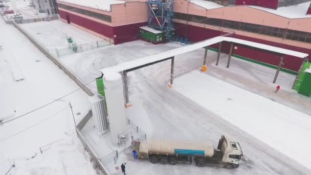 Camion à vue aérienne avec gaz liquéfié à l'usine sous la neige — Video