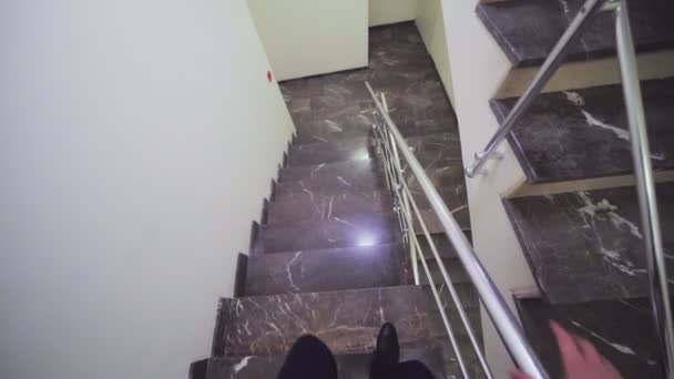 Businessman walks down marble stairs view from headcam — Stock Video