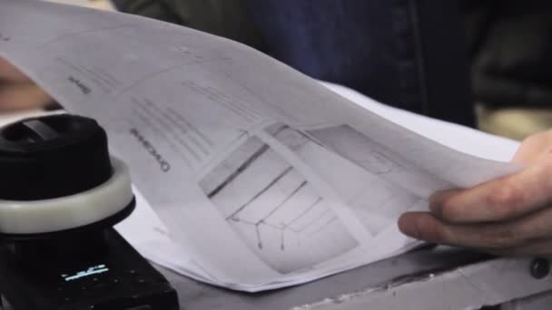 Чоловік тримає лист сценарію на маленькому столі в установці крупним планом — стокове відео