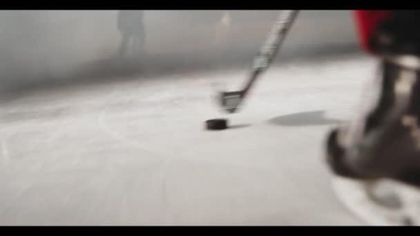 Хоккеист ведет черную шайбу к воротам вдоль катка — стоковое видео