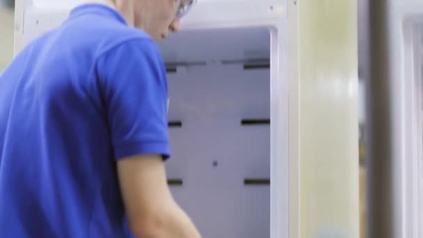Τύπος σε γυαλιά εγκαθιστά θήκες ραφιών μέσα στο ψυγείο — Αρχείο Βίντεο