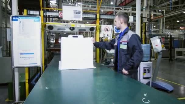 Pracownik sprawdza plastikową obudowę lodówki na przenośniku w sklepie — Wideo stockowe
