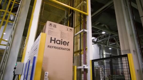 Fridge in logo box lifted up by machine at production plant — Stock Video
