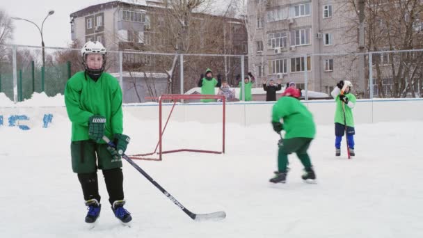 Kid hockeyspelare skjuter mål och springer iväg från beskyddare — Stockvideo