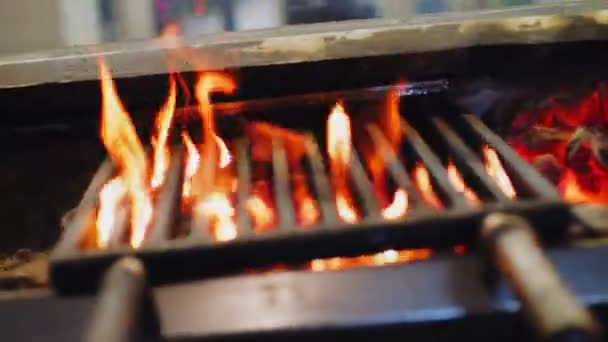 Estufa y el fuego ardiente bajo las rejillas de metal en la cafetería de comida de la calle — Vídeos de Stock