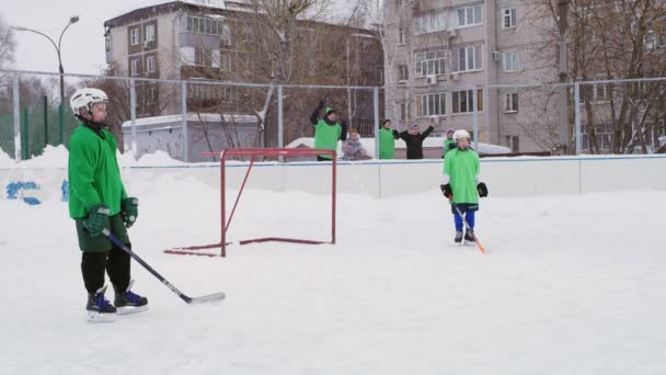 Menino jogador de hóquei carrega disco e chuta gol no inverno — Vídeo de Stock