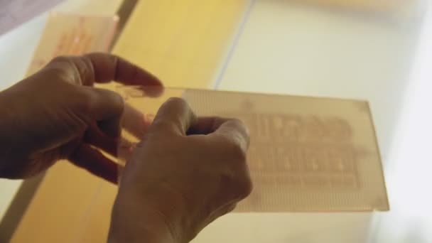 Anställd tar bort klistermärke från stencil och sätter på glas — Stockvideo