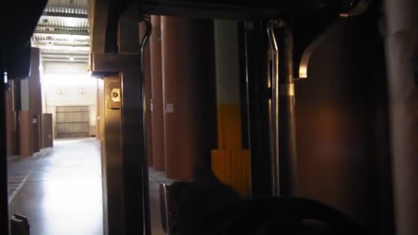 Человек ведет погрузчик вдоль склада с бумажными рулонами — стоковое видео