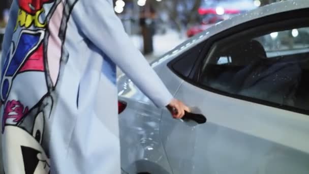 Fille en manteau avec impression de dessin animé obtient sur la voiture dans la rue — Video