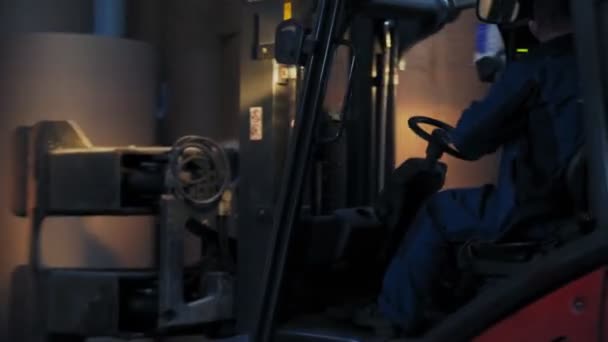 Ο άνθρωπος οδηγεί τον φορτωτή περονοφόρου μεταξύ κυλίνδρων χαρτιού στην αποθήκη — Αρχείο Βίντεο