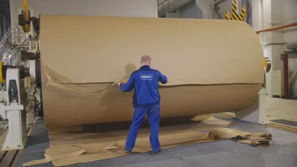 Робітник розрізає смужку коричневого паперу в фабричному складі — стокове відео