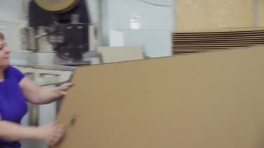 işçiler fabrikada kazık üzerine katlanmış karton kutular koymak