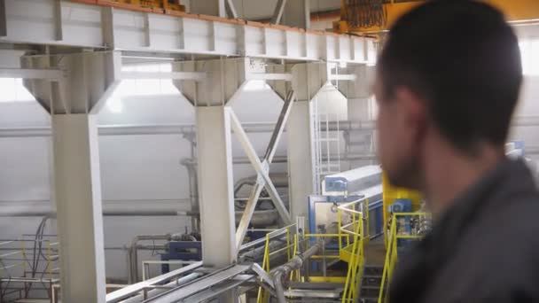 Работник смотрит на цех завода с современным оборудованием — стоковое видео