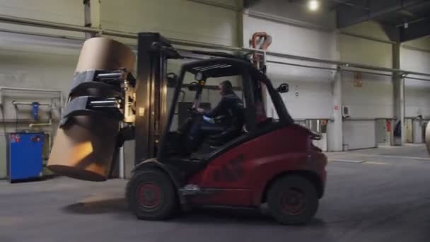 Trabajador impulsa cargador de la carretilla elevadora que lleva rollo de papel en almacenamiento — Vídeo de stock