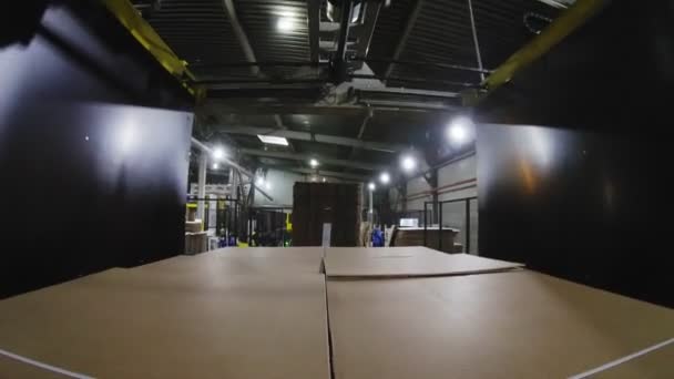 Tied folded cardboard boxes on conveyor belt in lit workshop — Stock Video