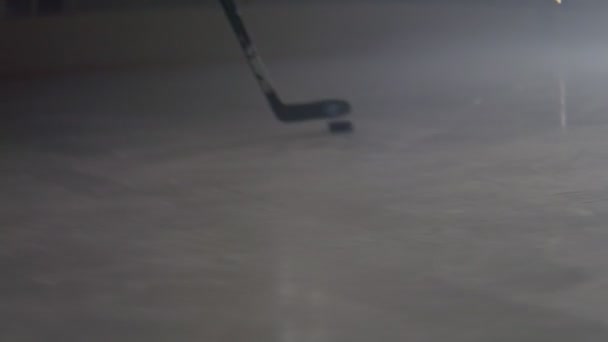 Хоккеист ведет шайбу с клюшкой на ледяной арене крупным планом — стоковое видео