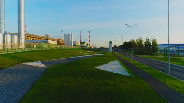 Lush lawn by gas and oil refinery plant under blue sky upper — ストック動画