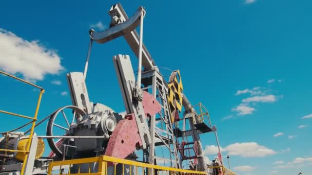Pump jacks stand on oil field against sky low angle shot — Stockvideo
