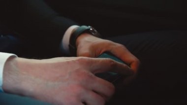 Takım elbiseli adam cep telefonuyla metro vagonunda oturuyor.