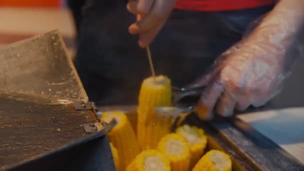 Человек берет и добавляет соль к вареной кукурузе в кафе крупным планом — стоковое видео