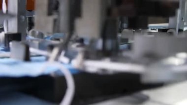 Üretim hattı elastik bantları mavi tıbbi maskelere bağlıyor