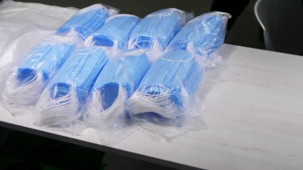 Plastic verpakkingen met blauwe beschermende medische maskers op tafel — Stockvideo