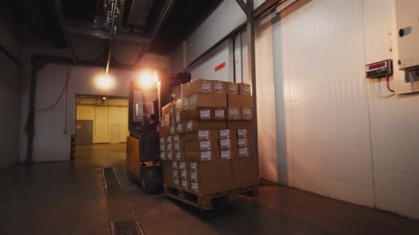 Man drives forklift loader with cardboard boxes in storage — Stock Video