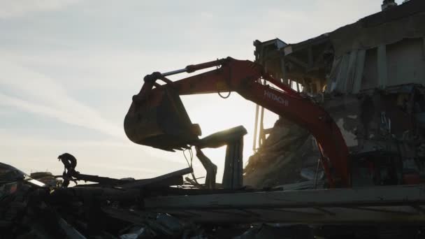 Silhueta de escavadeira desmantelando detritos do antigo estádio — Vídeo de Stock