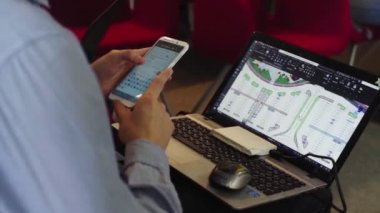 Adam, ofisinde grafik programı olan dizüstü bilgisayarın yanında telefon kullanıyor.