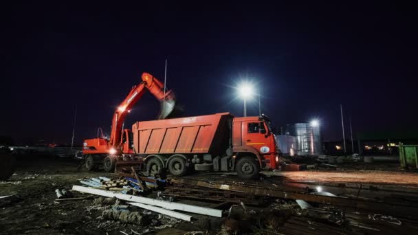 Екскаватор завантажує робочий корпус вантажівки з землею на будівництві. — стокове відео