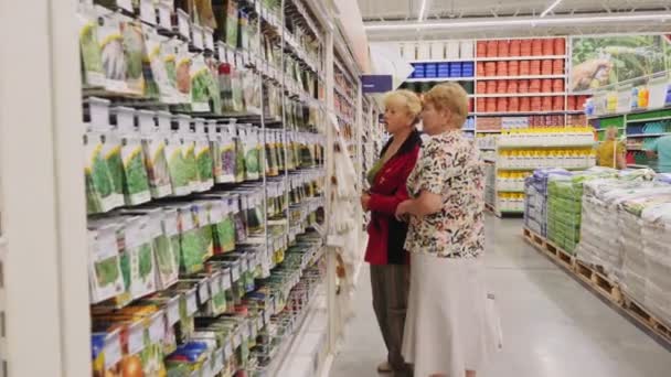 在花园超级市场，成熟的女人选择架子上的种子 — 图库视频影像