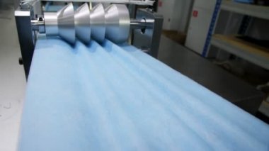 makine tek kullanımlık maskeler için kumaş şeritte kıvrımlar yapıyor
