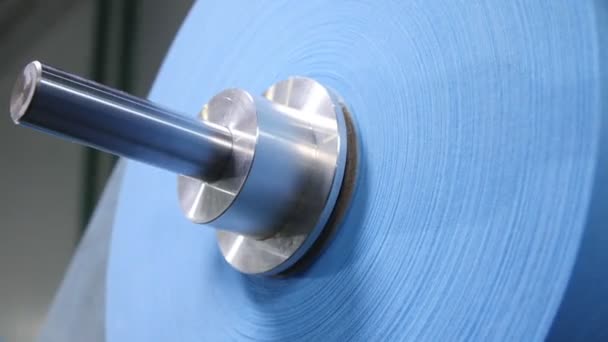 Blaue Stoffrolle für Schutzmasken auf Metallstange im Werk — Stockvideo