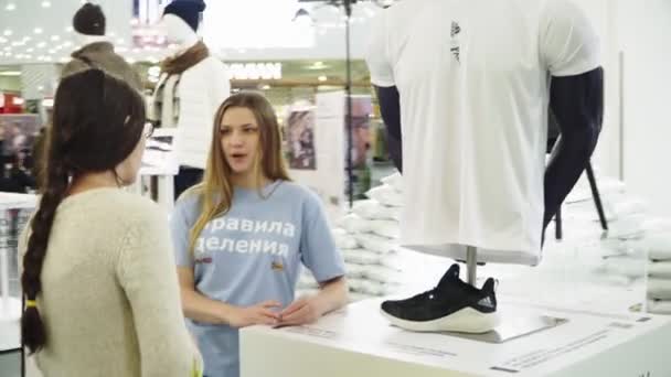 Volunteer talks to woman near stand at exhibition in hall — Stock Video