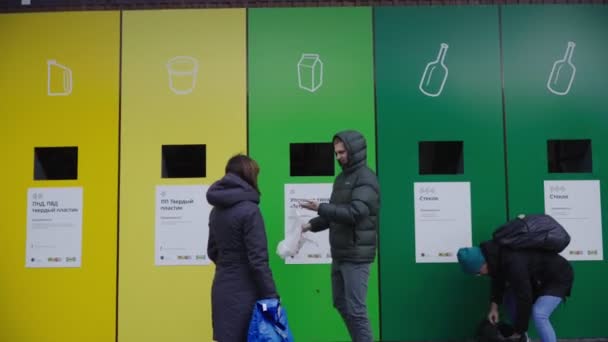 Люди кладут мусор в разноцветные банки на сортировочной станции — стоковое видео