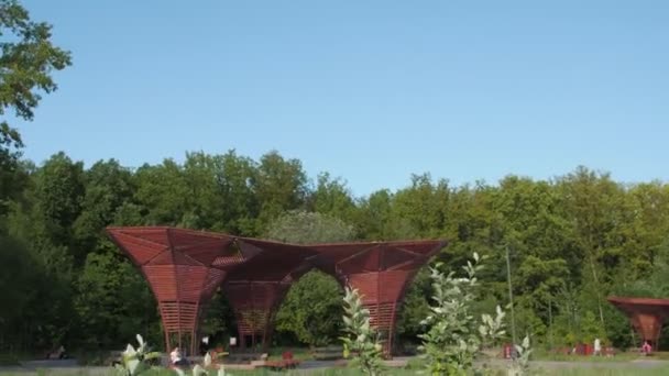 Parque de la ciudad con cenadores de madera bajo el cielo azul en el día soleado — Vídeo de stock