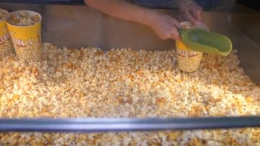 Kişi kovayı koyar ve kafede patlamış mısır karıştırır.