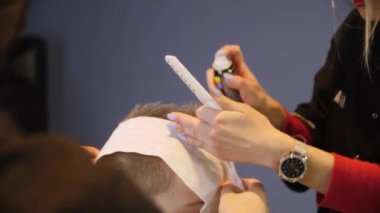 Taraklı kağıt ve spreyli sarışın adamı mohawk yapıyor.