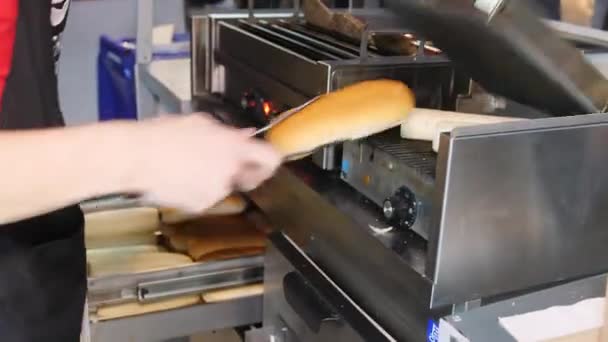 Mujer calienta bollos para preparar deliciosos hot dogs en la cafetería — Vídeo de stock