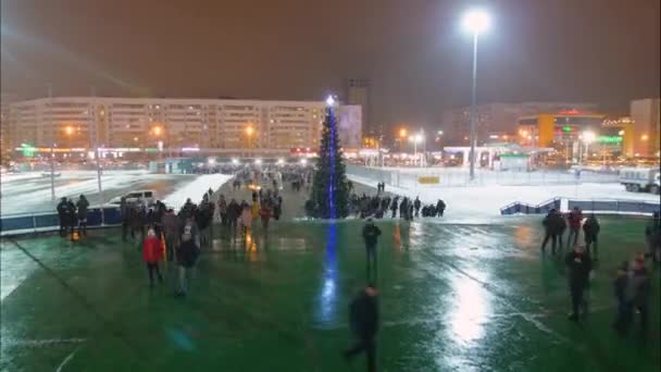 Menschen laufen am Weihnachtsbaum vorbei, um Sportwettkämpfe zu verfolgen — Stockvideo