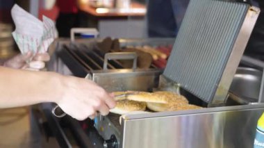 Kadınlar fast food kafede hamburger hazırlamak için taze çörekler ısıtır.