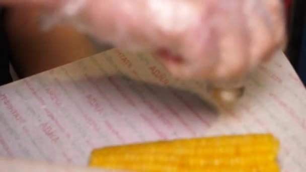 Чоловік додає сіль до вареної кукурудзи на коб у вуличному кафе швидкого харчування — стокове відео