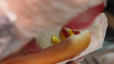 Çalışan ketçap döker ve taze çöreğe sosis koyar.